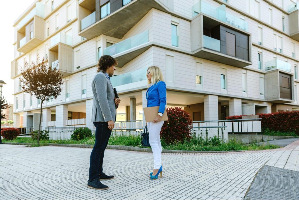 Young professionals discussing apartment options outside a North Dallas high-rise